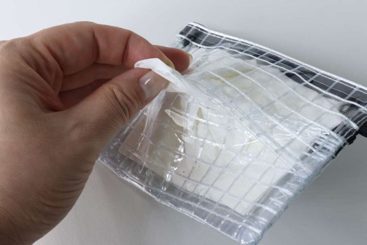 マルチケースのティッシュ取り出し口から白いティッシュを引き出す手
