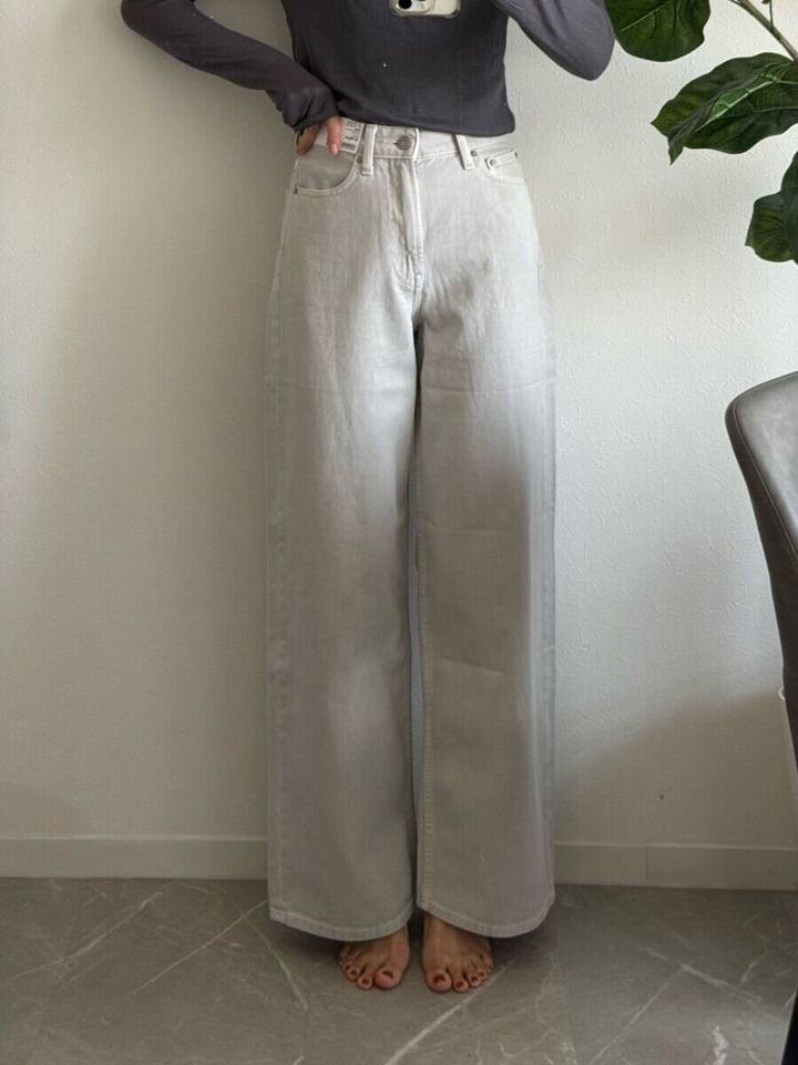 ライトグレーのワイドジーンズを着用し正面を向いて立つ女性