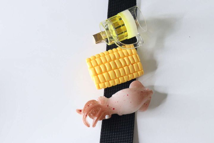 黒いベルトにビールジョッキ、コーン、イカのヘアクリップを挟んで飾っている