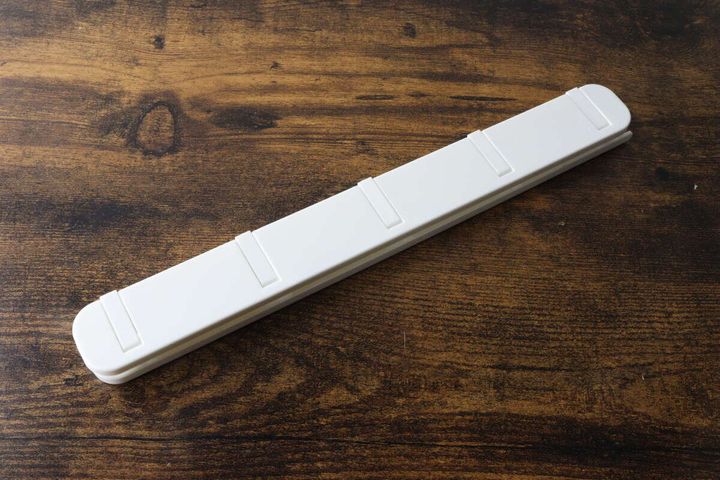 木目調のテーブルに置かれた白い粘着スライド式5連収納フック本体