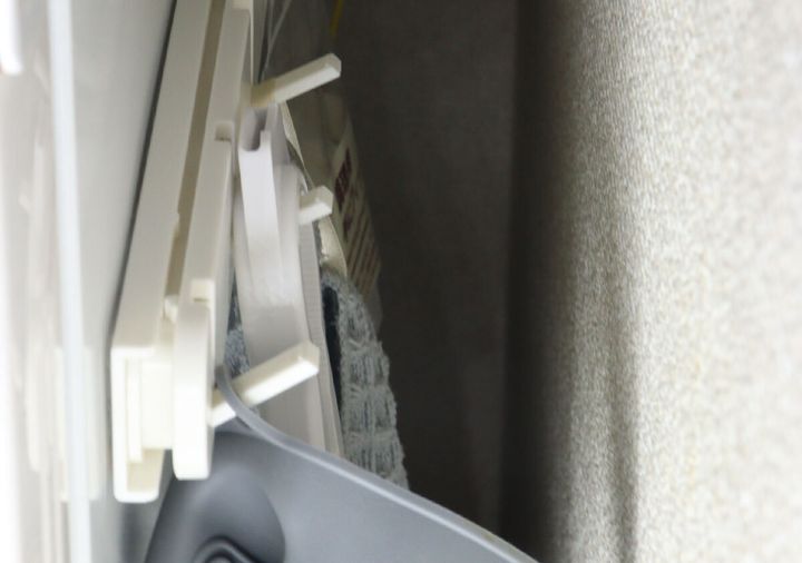 狭い隙間に取り付けられた白い収納フックに、ミトンやタオルなどの小物が掛けられている様子