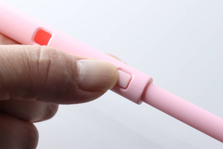 指でピンク色の支柱の伸縮ボタンを押しているクローズアップ