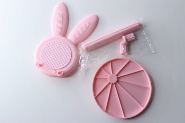 ピンク色のウサギ型スマホスタンドのパーツが分解された状態で置かれている