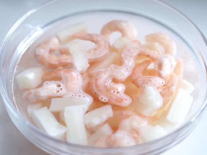 ボウルに入った冷凍シーフードミックスを塩水で解凍している
