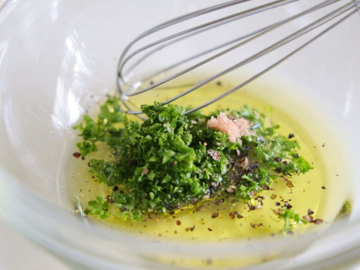 ボウルに入ったオリーブオイル、パセリ、調味料を泡立て器で混ぜている