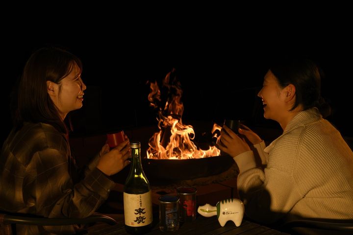 焚火を囲みながら日本酒を楽しむ様子