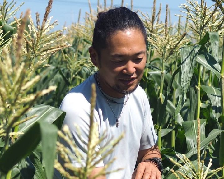 とうもろこし畑に立つ玉蜀黍儂人・彦坂航さん