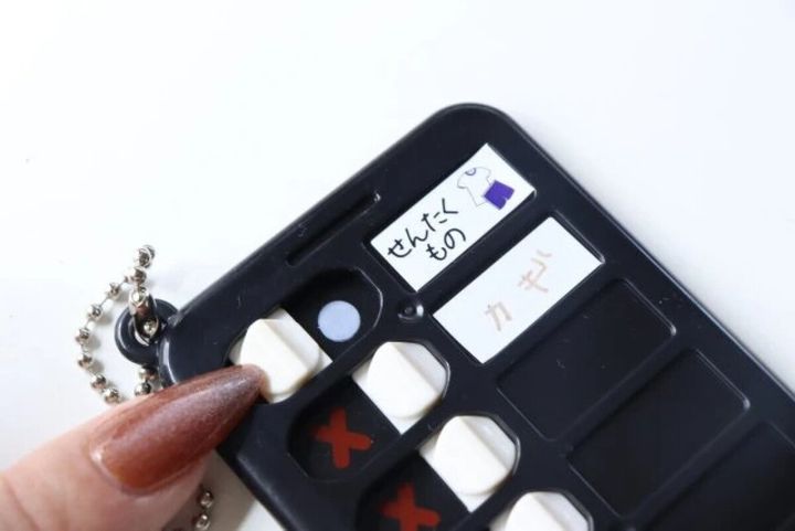 黒いチェッカーキーホルダーに「せんたくもの」「カギ」と書かれたシールが貼られている
