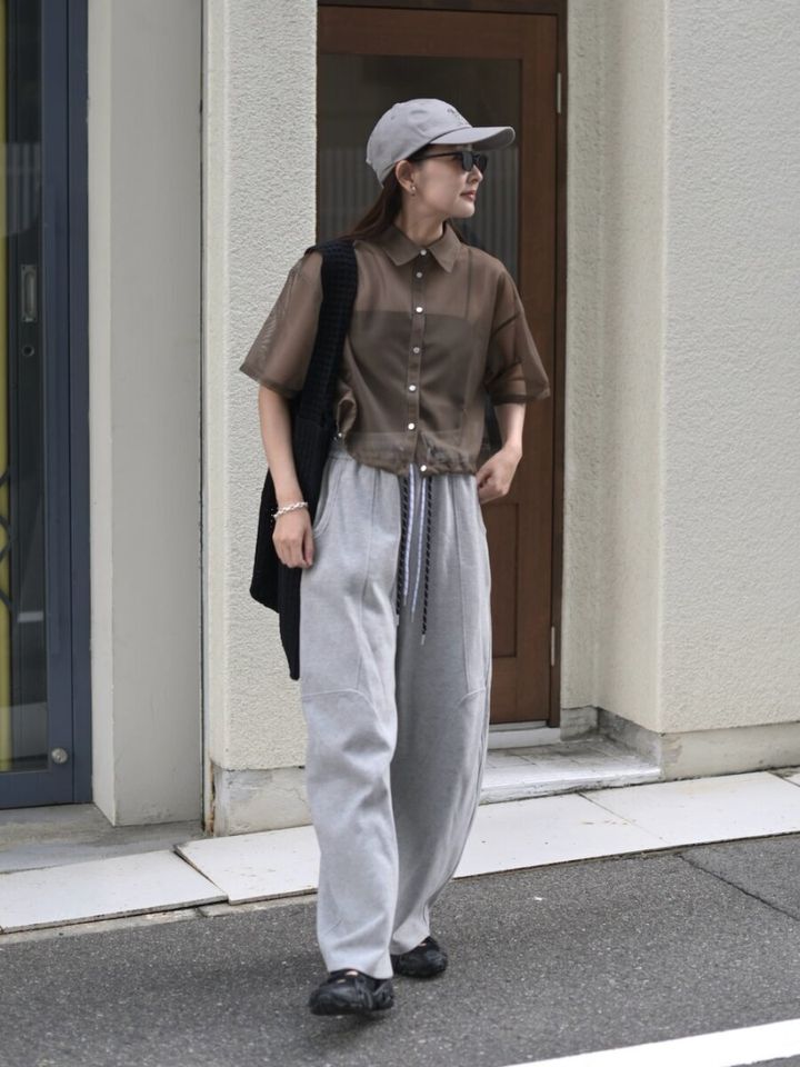 ブラウンのシアーシャツとグレースウェットパンツ姿の女性