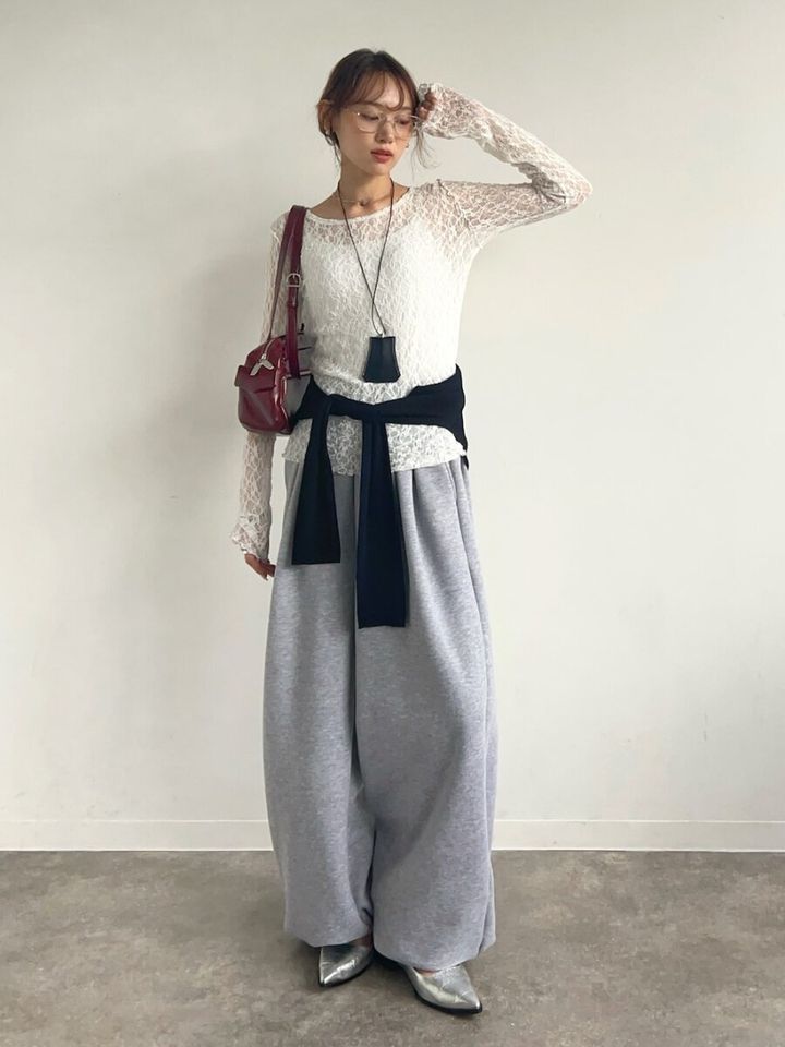 白レーストップスとグレースウェットパンツ姿の女性