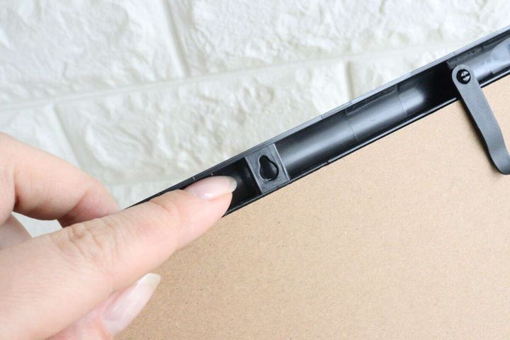 黒いA4フォトフレーム裏側の壁掛け用フック穴を指す