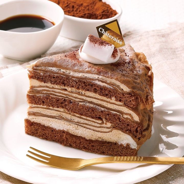 金色のフォークが添えられたチョコレート色のクレープケーキの断面