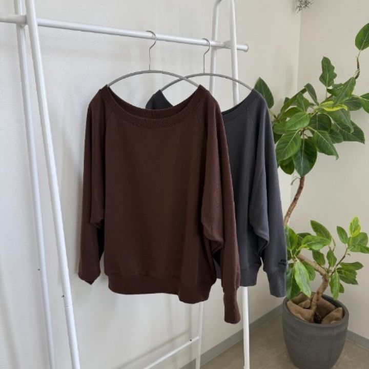 ブラウンとグレーのゆったりとしたプルオーバートップスがハンガーに並んでいる
