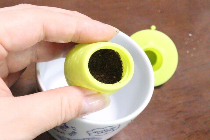 女性の指がティーストレーナーの下部に茶葉を入れている様子