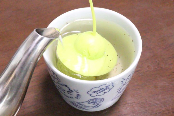 カップに入れたティーストレーナーにやかんからお湯を注いでいる様子