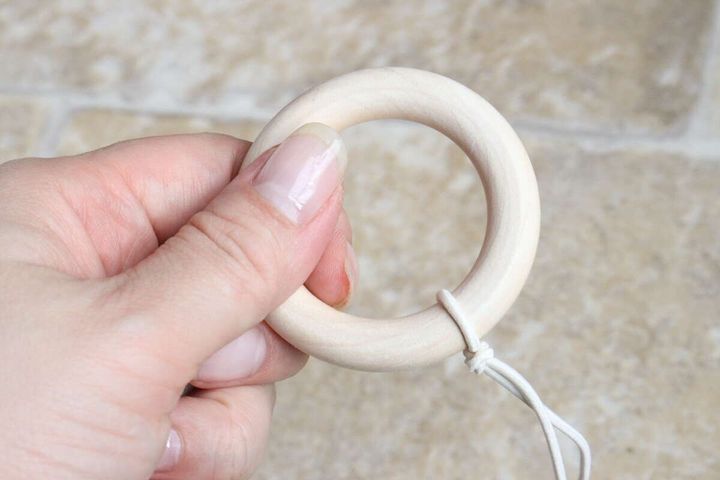 女性の手が、猫用おもちゃの木製リングハンドルを握っている様子