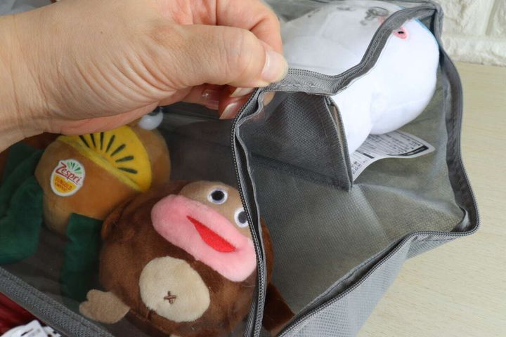 ぬいぐるみ収納ポケットのファスナーを開け、ぬいぐるみを入れようとしている手元