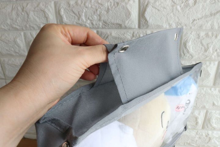 ぬいぐるみ収納ポケット上部の吊り下げ部分を裏返して見せている手