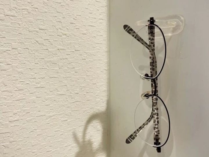 壁に貼ってはがせるフィルムフックでメガネが吊るされている