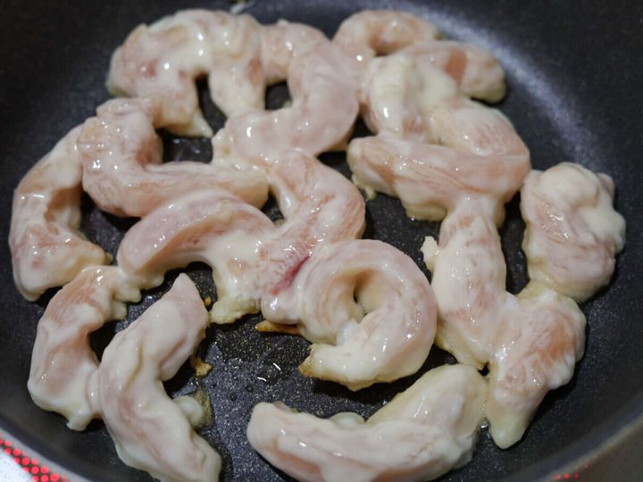 フライパンで衣をまとった鶏むね肉を焼いている