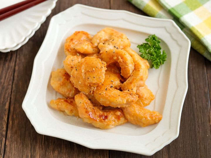白い皿に盛り付けられた鶏マヨと布巾が置かれた食卓