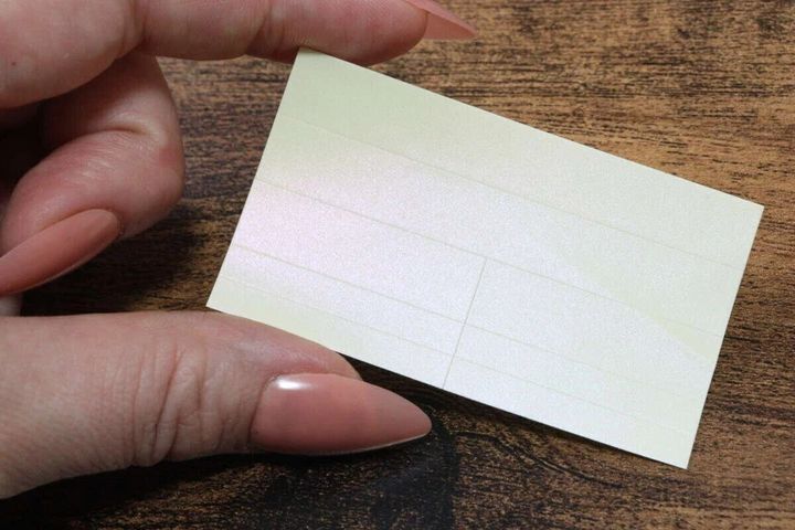 女性がパステルカラーの反射ラベルを指でつまんで見せている