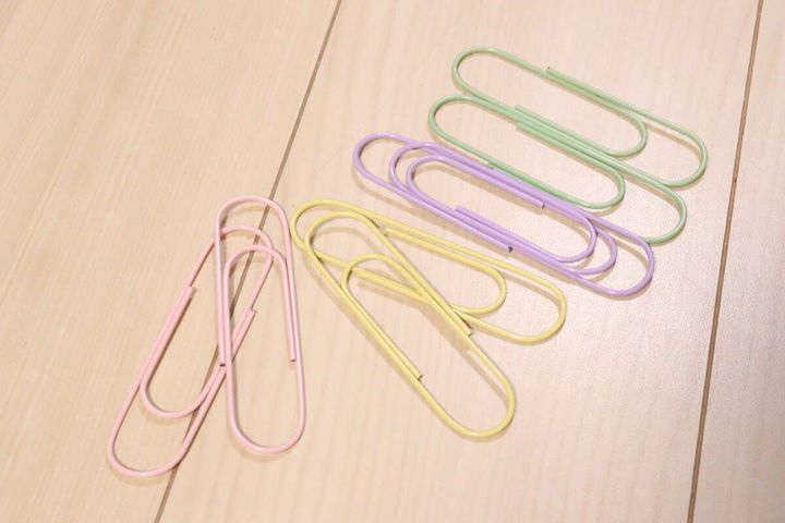 ピンク、イエロー、パープル、グリーンのビッグクリップが床に並べられている