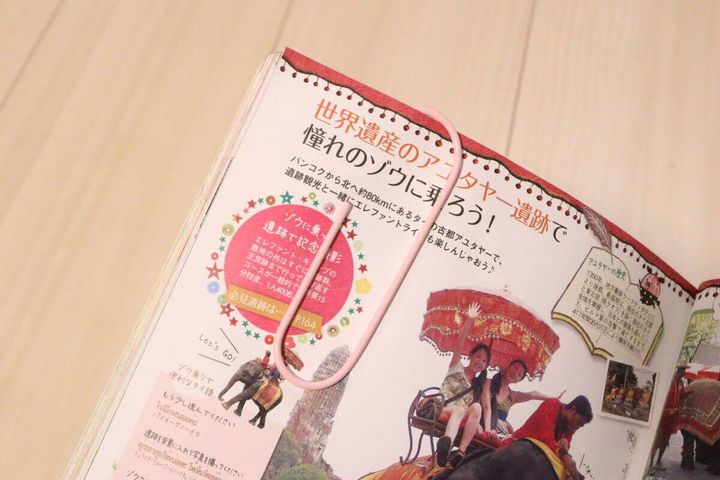 開いた雑誌のページにピンクのビッグクリップがブックマーカーとして挟まっている