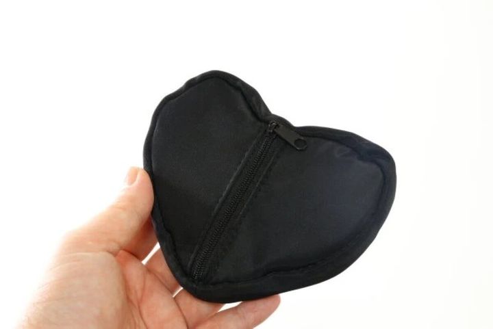 手のひらに乗せられた黒いハート型ポーチの背面