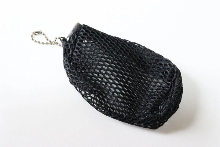 黒いメッシュ素材のポーチがボールチェーン付きで置かれている