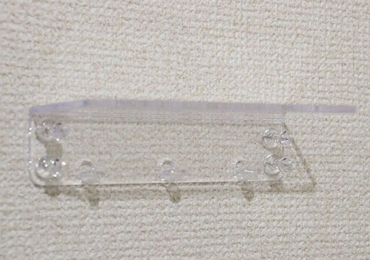 透明なウォールラックの裏側、ピンを差し込む穴が見える