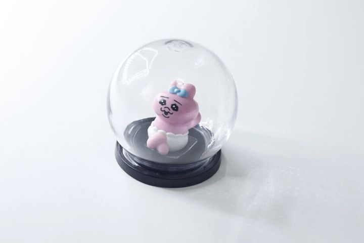 透明なディスプレイドームの中に、ピンクのうさぎのフィギュアが飾られている