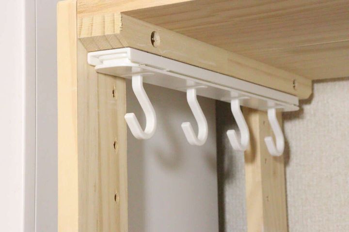 木材で組まれた棚板の下に白い粘着スライド式4連フックが取り付けられている様子