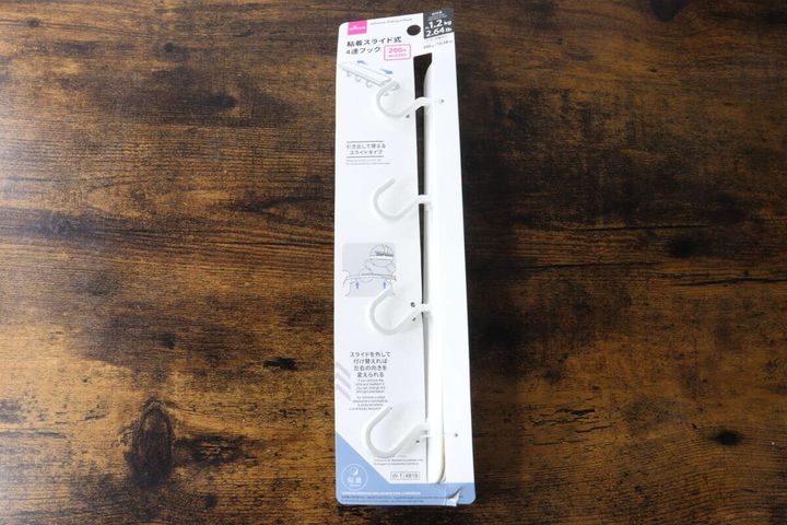 木目調のテーブルに置かれたダイソー粘着スライド式4連フックのパッケージ