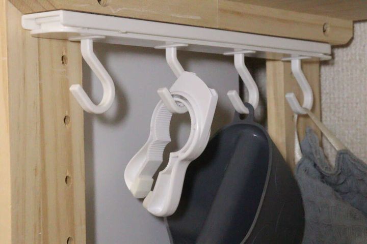 棚板下のフックに鍋つかみやミトンなどのキッチン小物が掛けられている様子