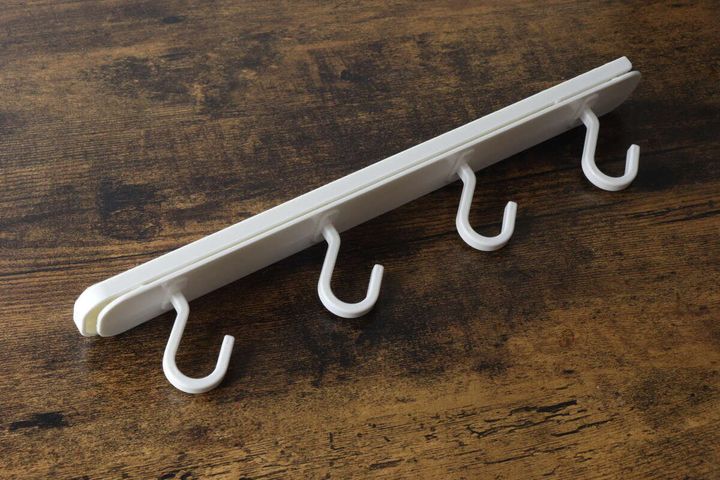 木目調のテーブルに置かれた白い粘着スライド式4連フックの本体