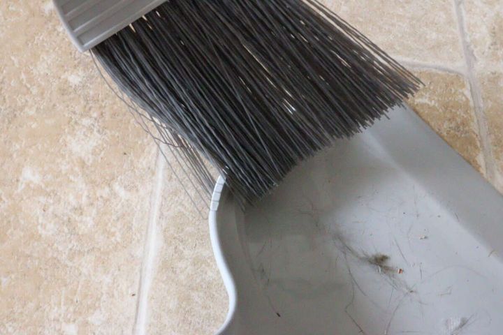 ちりとりのギザギザ部分でほうきの毛に絡んだゴミを取っている