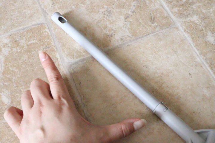 ほうきの柄の長さを指で示している手元のアップ