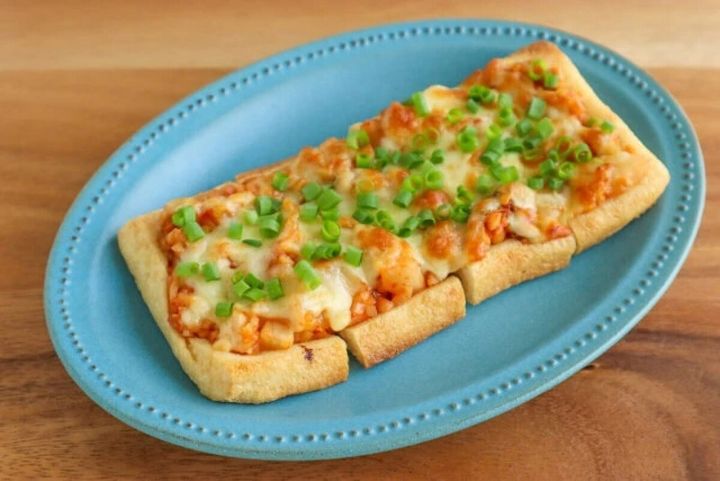 青い楕円皿に盛られた納豆キムチ油揚げピザ