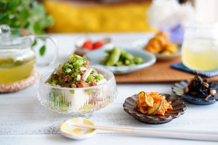 薬味をのせたツナ納豆冷奴と副菜が並ぶ食卓