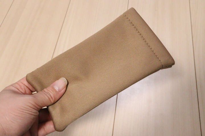 ベージュ色の布製メガネケースを片手で持っている様子
