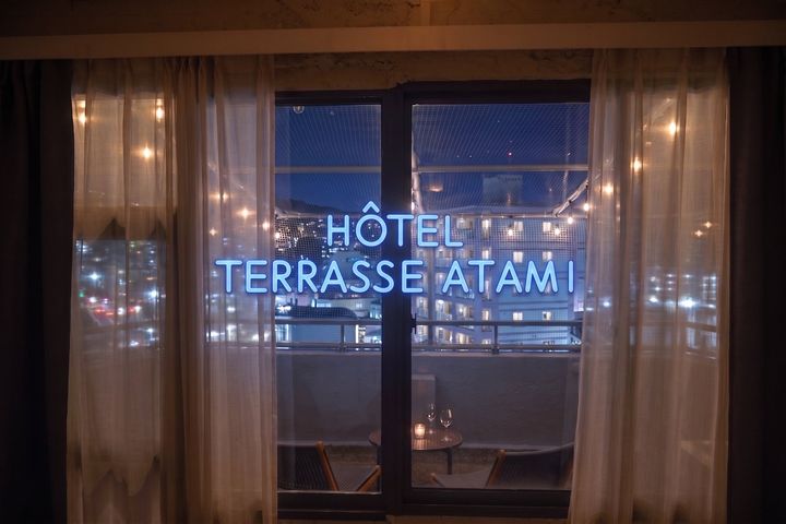 HOTEL TERRASSE ATAMIの客室から見た夜の商店街とネオンサイン