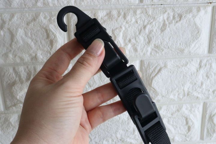 女性の手がヘッドレスト用お買い物フックのベルト部分を持つ