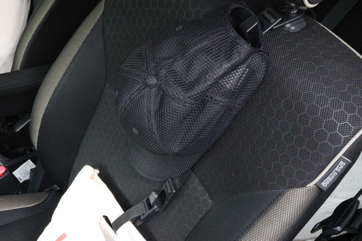 車の助手席に黒い帽子と白いバッグが置かれている