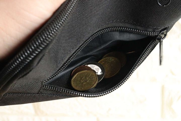 黒いポーチのフロントポケットに小銭が数枚入っている様子