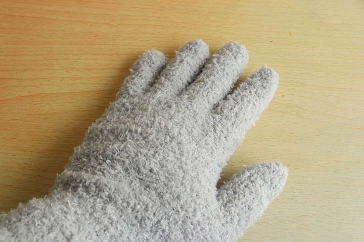 木目のテーブルに置かれた、グレーのホコリ取り手袋をはめた手のひら