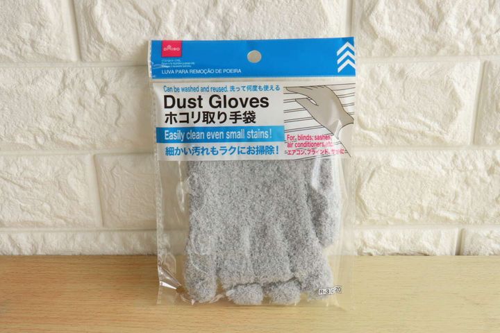 白いレンガ調の壁を背景に「ホコリ取り手袋」のパッケージが置かれている