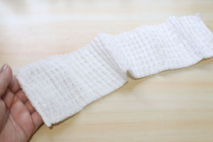 手で広げられた白いボディタオルが伸びている様子