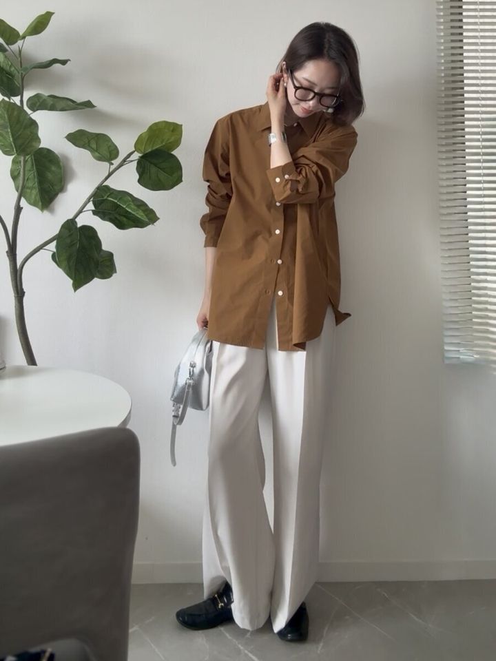 ブラウンシャツを白ワイドパンツに合わせた女性