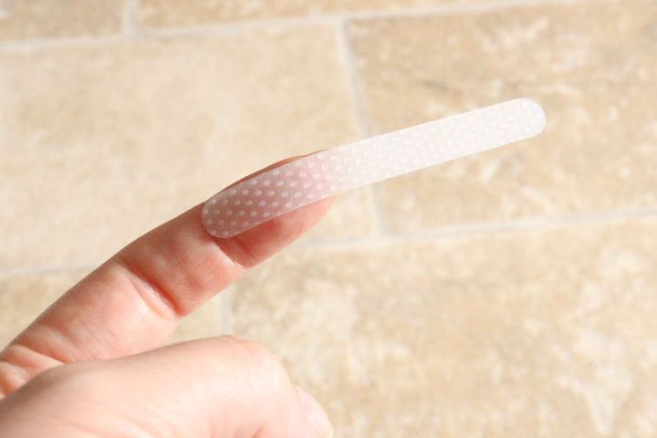 女性の指先に半透明の滑り止めシリコーンシールを乗せて薄さを示している